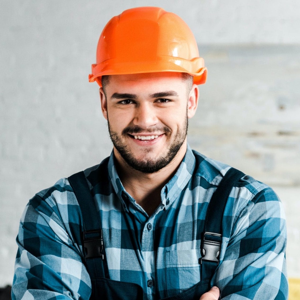 cheerful handyman looking at camera while standing with crossed arms